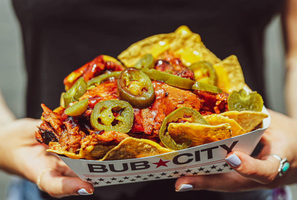 Image shows a plate of barbecue nachos propped up by someone wearing a shirt that says "Smokeout"