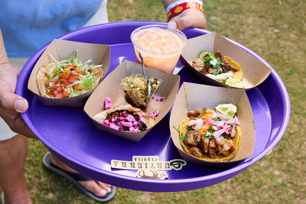 Image shows someone holding a tray of tacos at Texas Monthly Taco Fest.