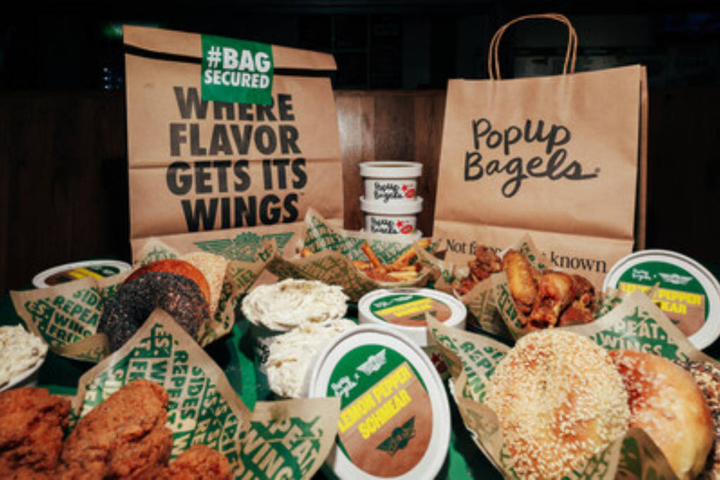 Image shows Wingstop bags propped up behind a table of bagels.