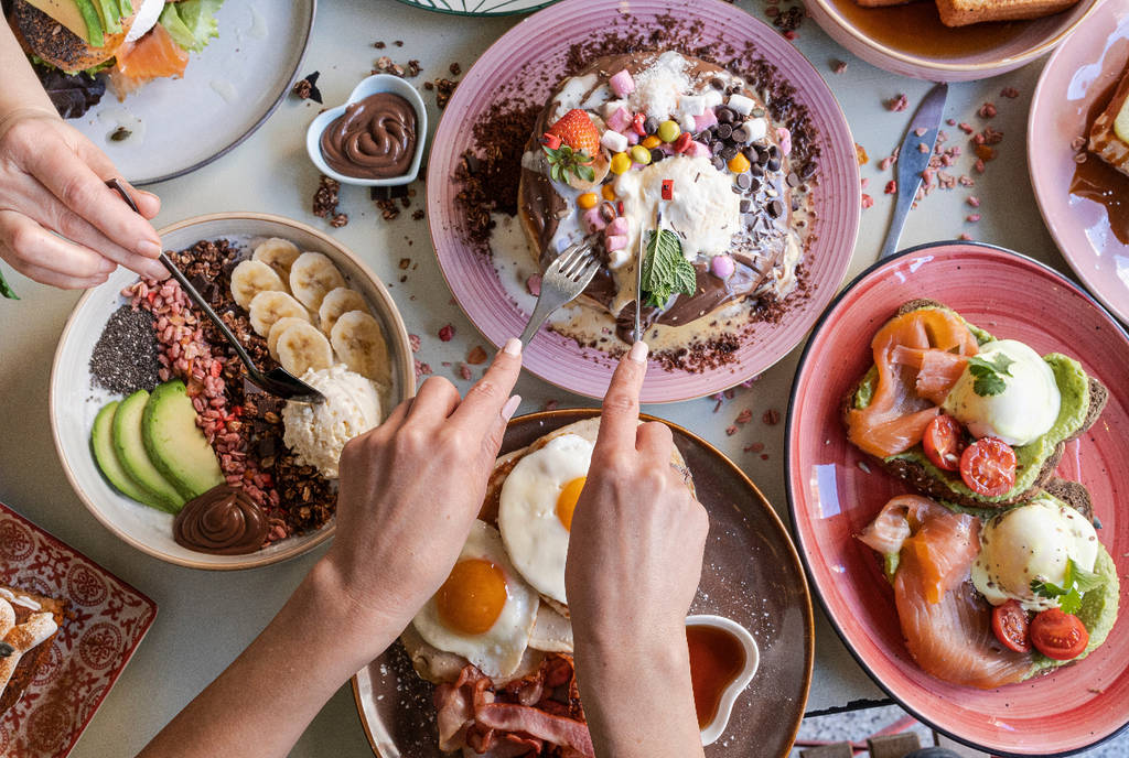 Image shows a person eating brunch food.