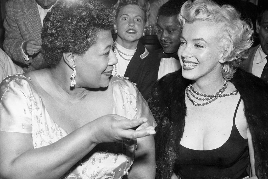 Image shows a photograph of Ella Fitzgerald speaking with Marilyn Monroe. 