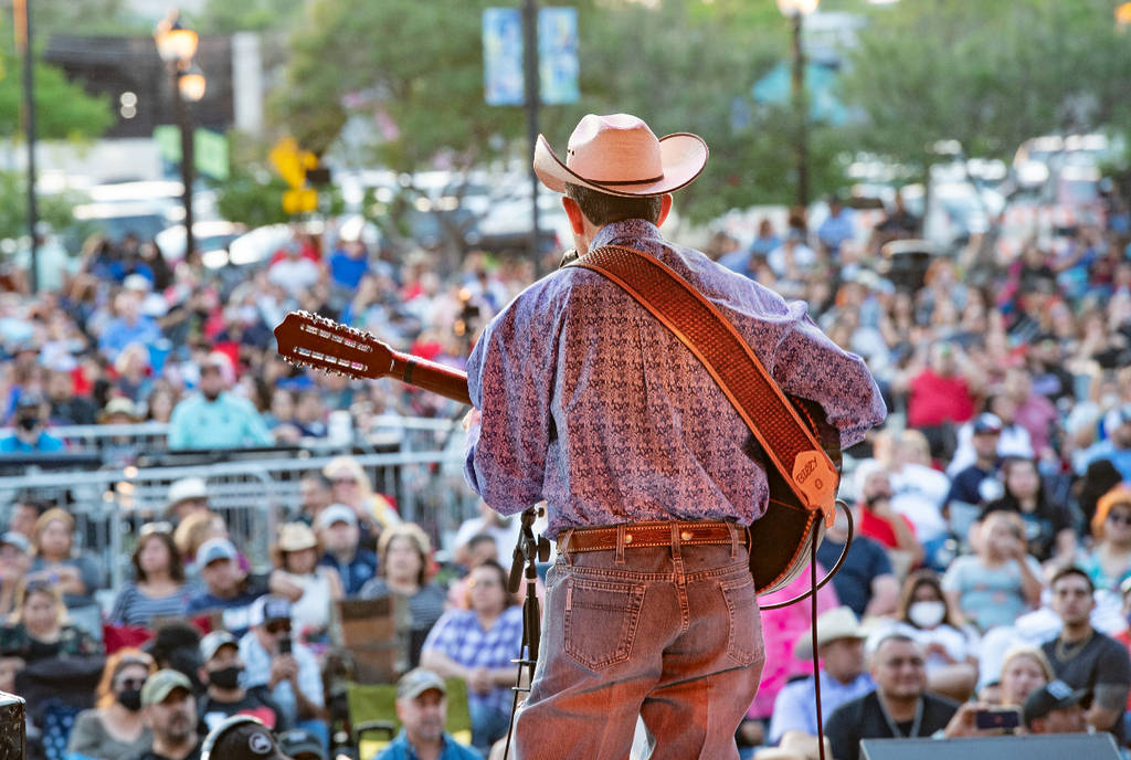 La imagen muestra a un músico actuando en el escenario del Levitt Pavilion en Arlington, Texas.