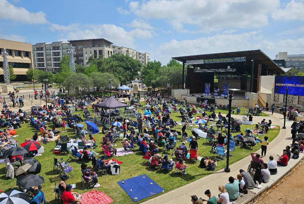 La imagen muestra el Levitt Pavilion en Arlington con una multitud de gente en un día soleado.
