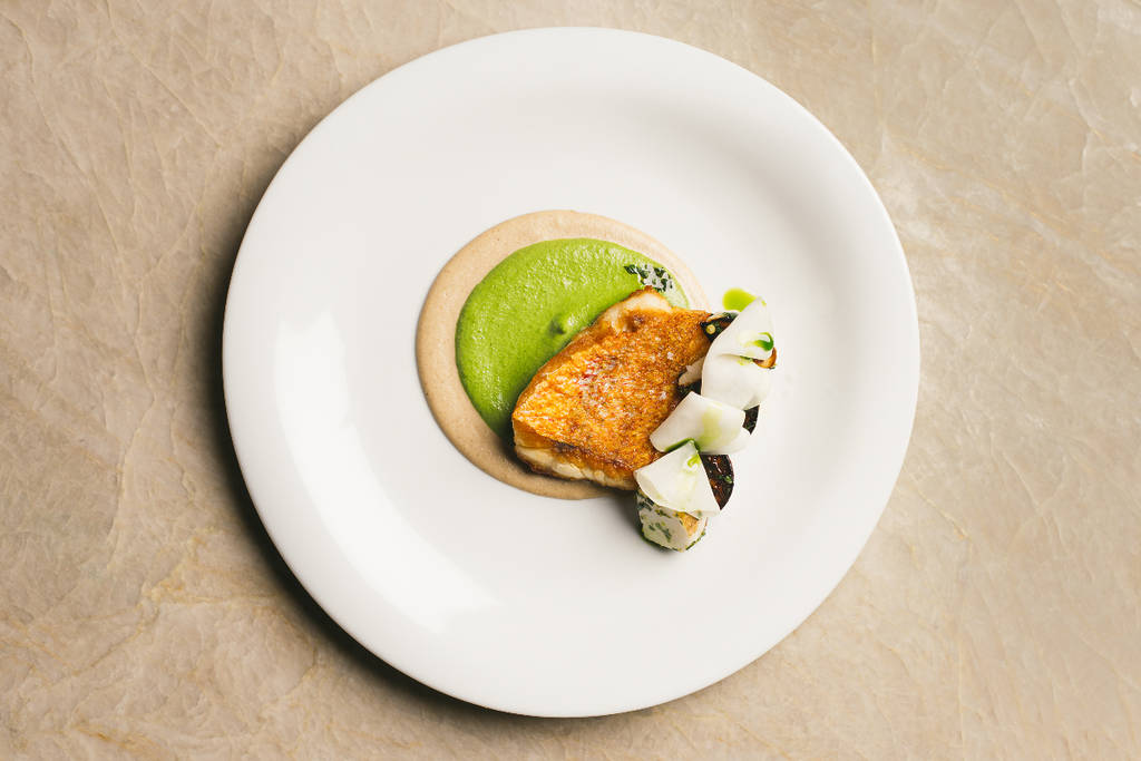La imagen muestra un plato, elegantemente emplatado, en el restaurante Oloyo de Dallas.