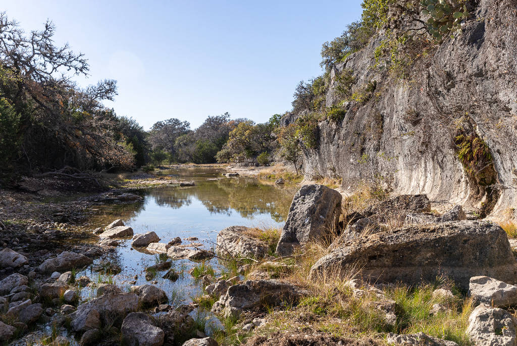 La imagen muestra una pared rocosa y un pequeño estanque en el Parque Estatal Silver Lake, en Texas.