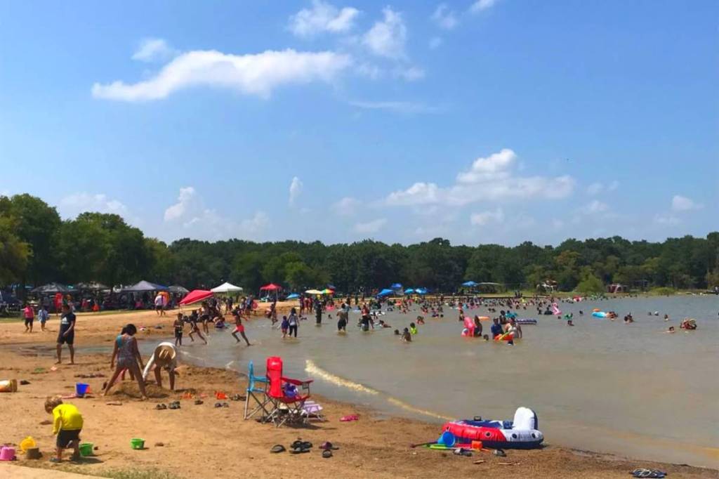 Image shows people visiting the beach at Isle du Bois at Ray Roberts Lake State Park in Texas. 