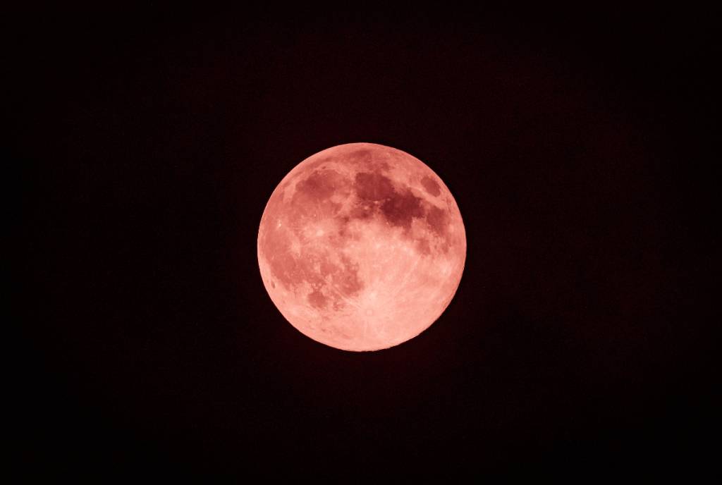La imagen muestra la Luna de Fresa contra el fondo de una noche oscura. 