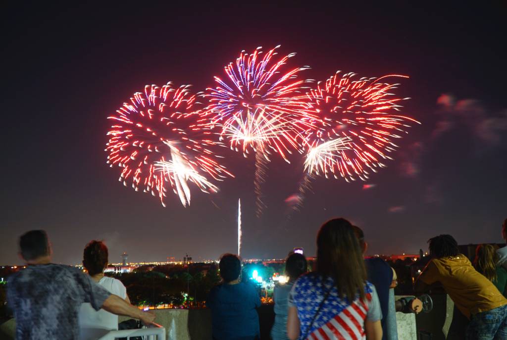 La imagen muestra a gente viendo un espectáculo de fuegos artificiales en el Addison Kaboom Town!