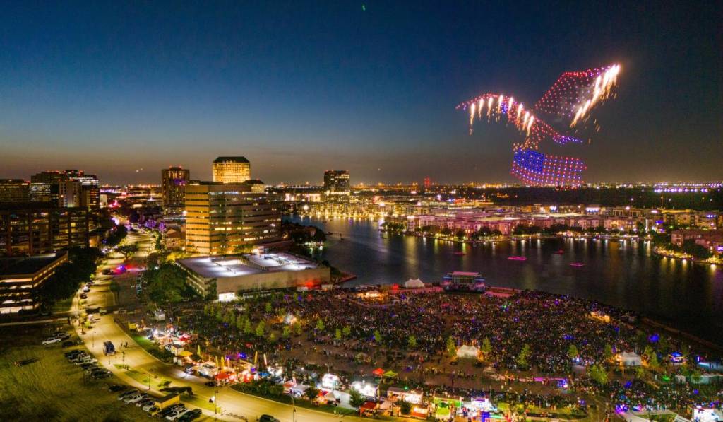 La imagen muestra el evento «Irving Stars & Stripes» con un espectáculo patriótico de drones. 