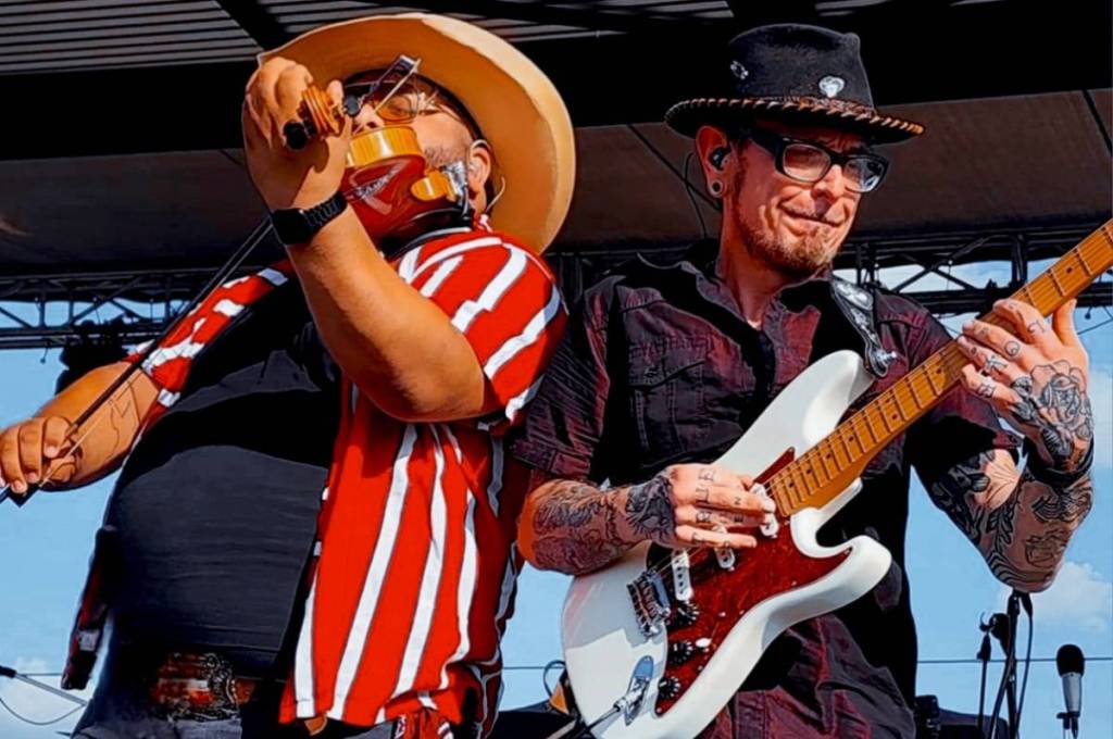 Image shows two musicians performing on stage. 