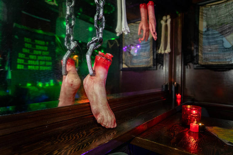 La imagen muestra una espeluznante decoración de Halloween que incluye elementos que parecen un pie y una mano cortados colgados de ganchos. 