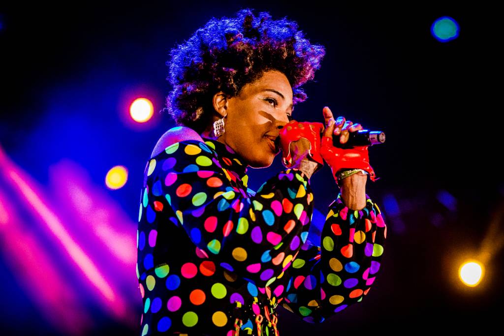 La imagen muestra a una mujer cantando con un micrófono en el escenario.