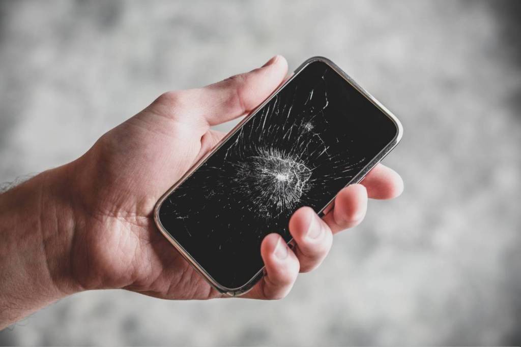 La imagen muestra a una persona con un smartphone con la pantalla rota.