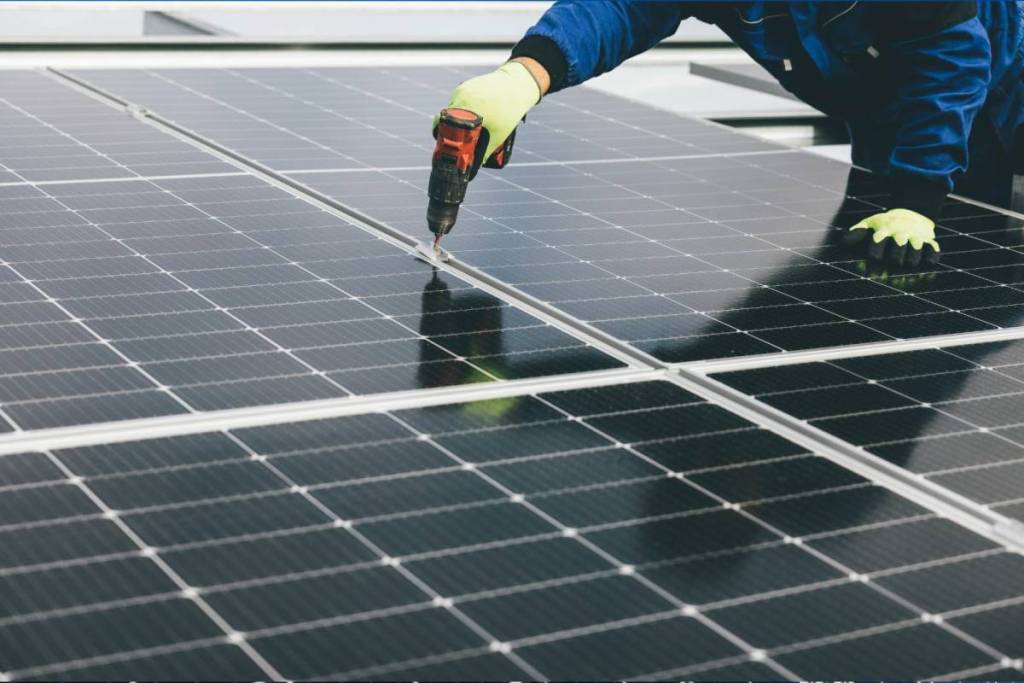 La imagen muestra a una persona trabajando en unos paneles solares. 