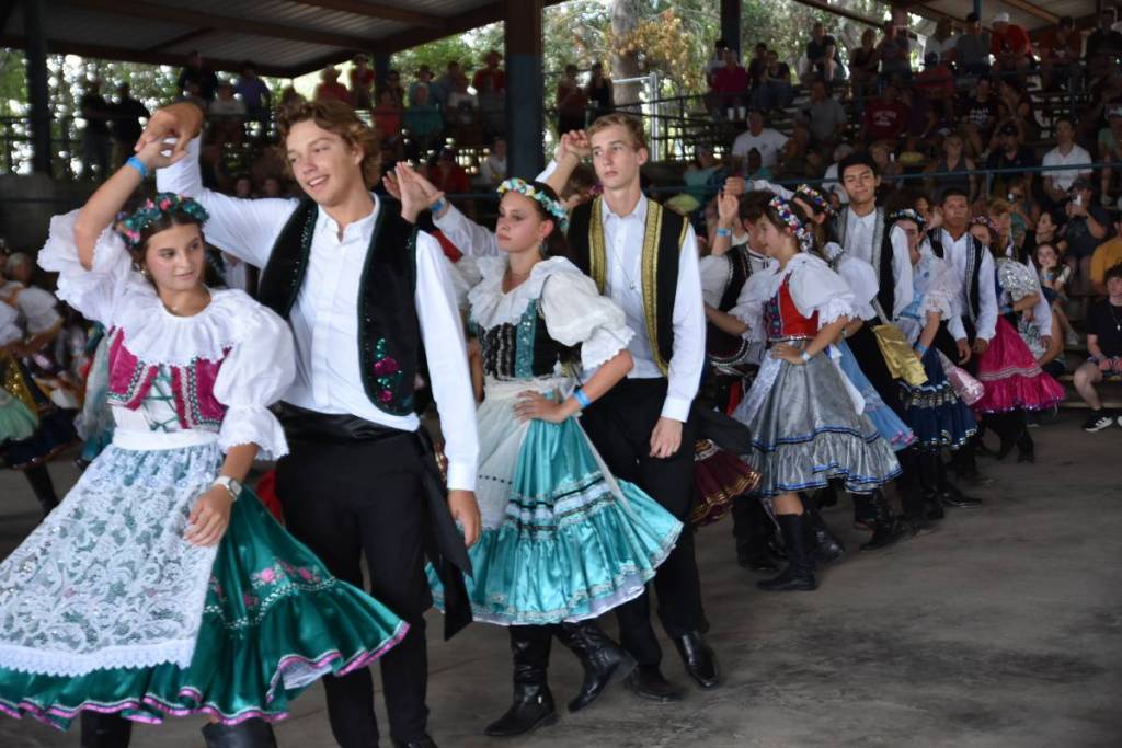 La imagen muestra a un grupo de personas bailando con trajes tradicionales checos.