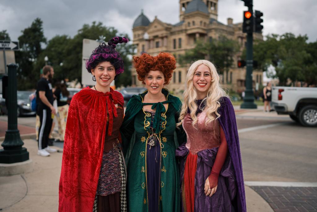Image shows three women dressed as characters from the movie "Hocus Pocus" in front of the Denton courthouse.