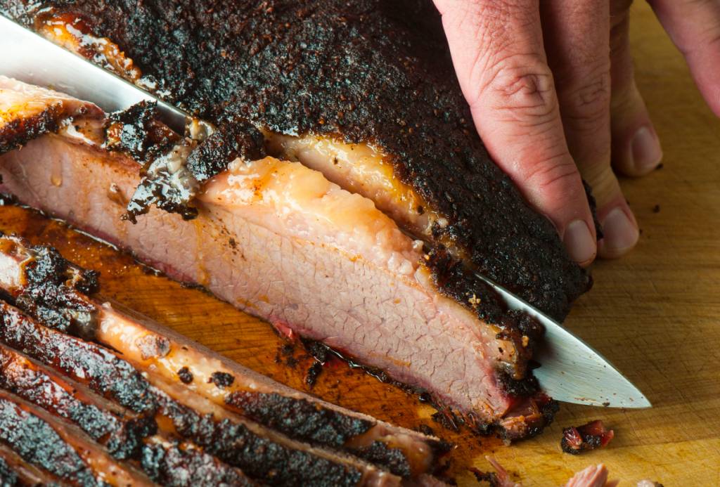 Image shows someone slicing brisket.