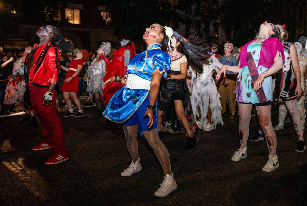 La imagen muestra a gente bailando en una fiesta callejera de Halloween. 