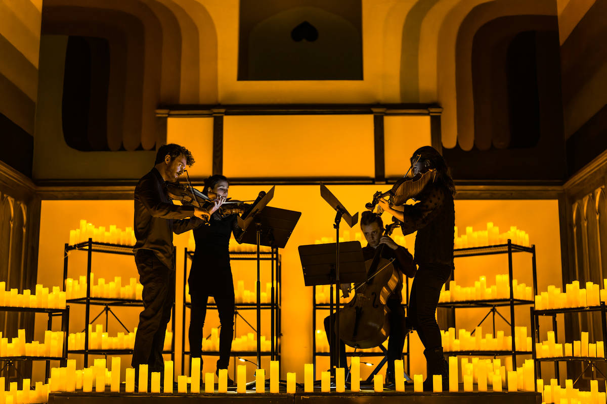 A string quartet perform, surrounded by candles at a Candlelight concert.
