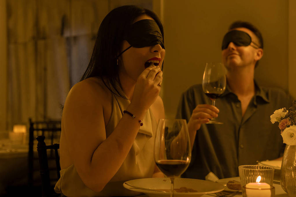 A woman eats with a blindfold at Dining in the Dark.
