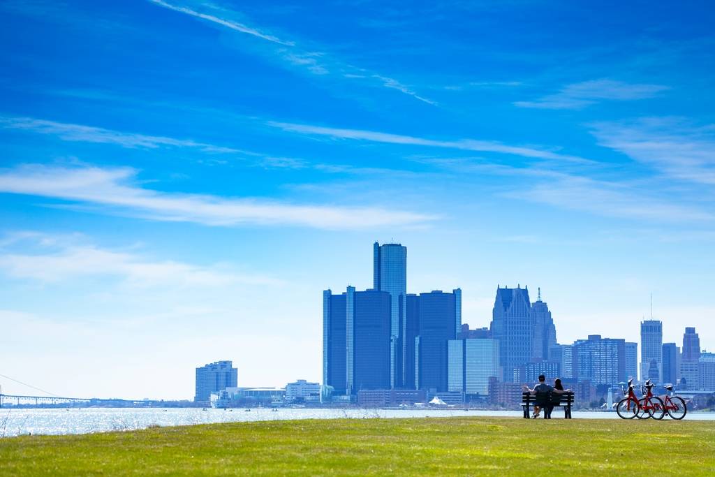 Detroit river with view of downtown and lovely couple sit in the bench on Sunset Point over from Belle Isle