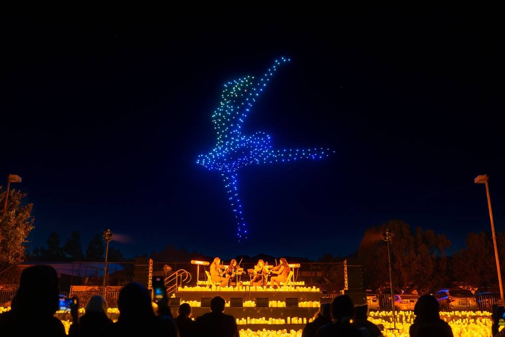 Illuminated drones take flight overhead a candlelit string quartet
