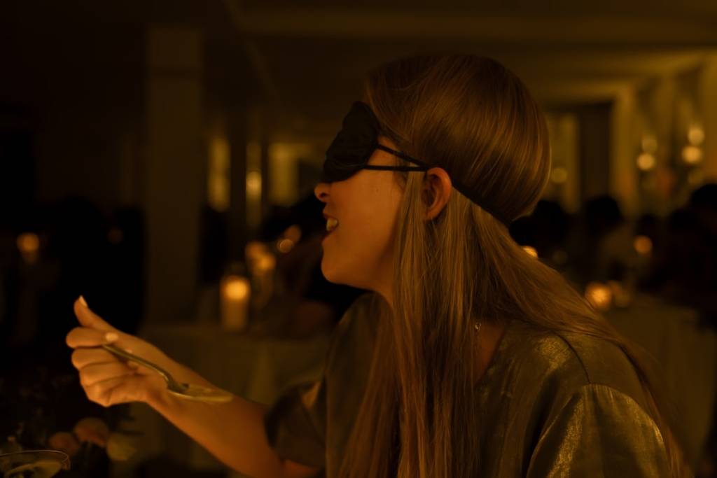 A woman blindfolded eating at a Dining in the Dark experience