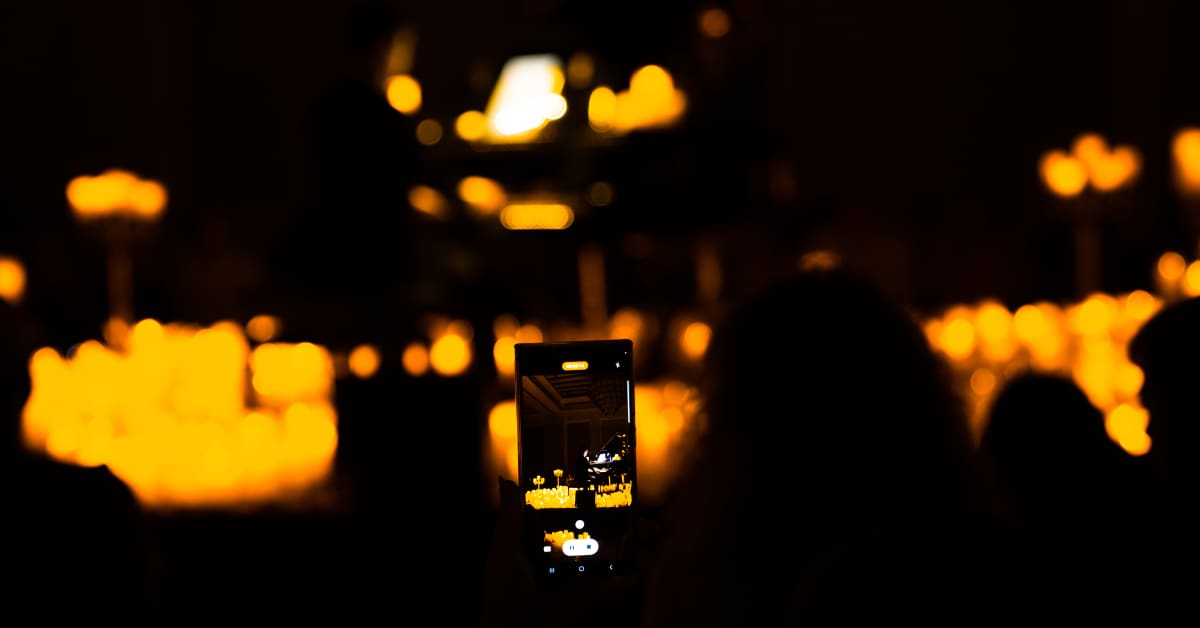 The silhouette of a woman snapping pictures of a Candlelight concert