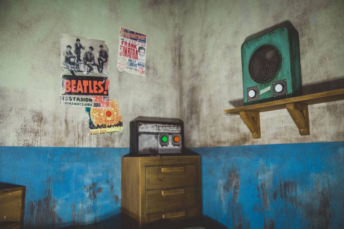 A prison cell consisting of a radio, speaker and posters.