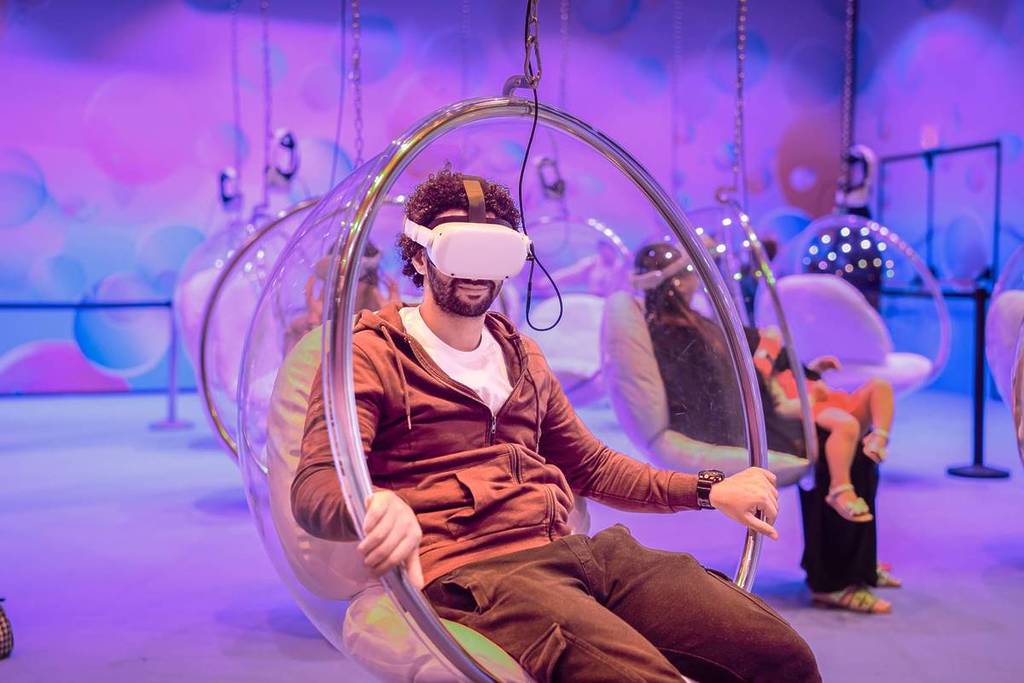 Un ospite si diverte con il simulatore VR di Bubble Planet Al Ain mentre è sospeso al soffitto su una poltrona a bolla