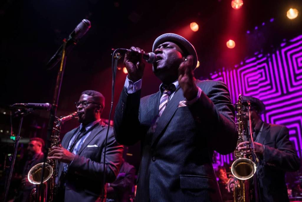 A blues band performing live on a dimly lit stage at The Jazz Room tribute to the blues