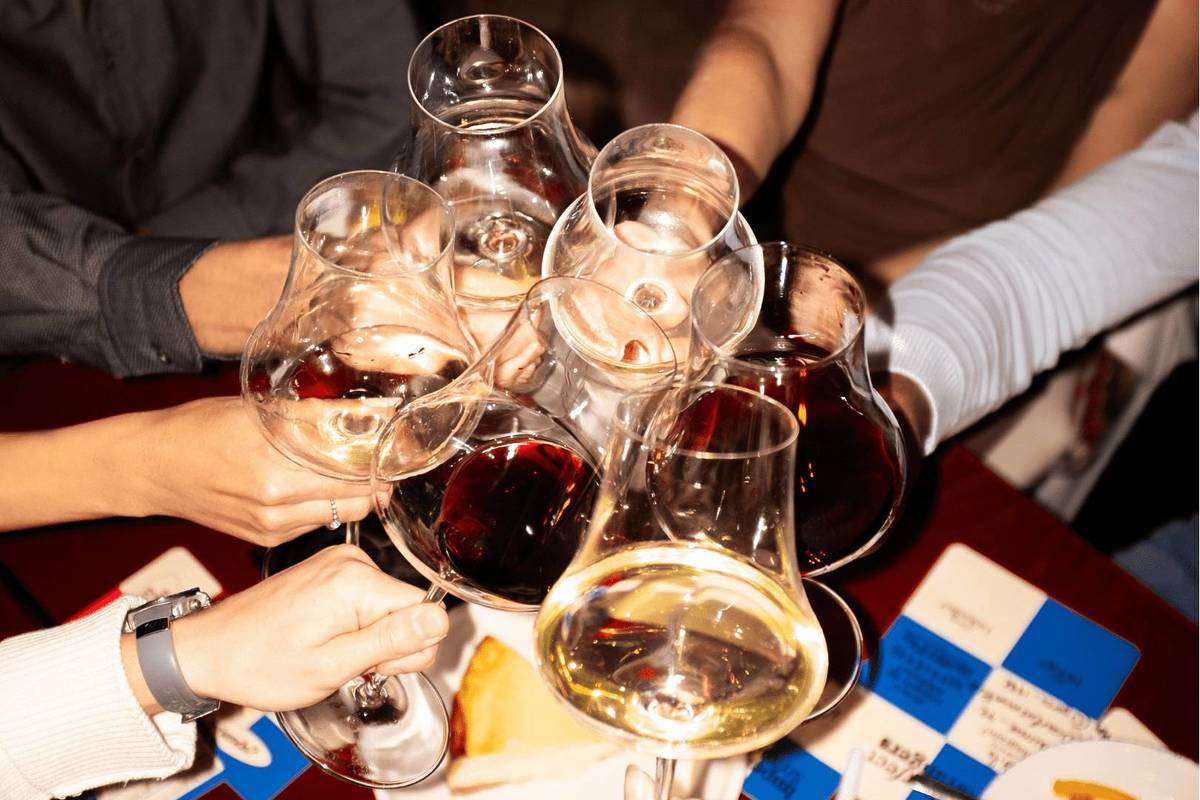 Wine glasses being cheersed together at a The First Round dinner event