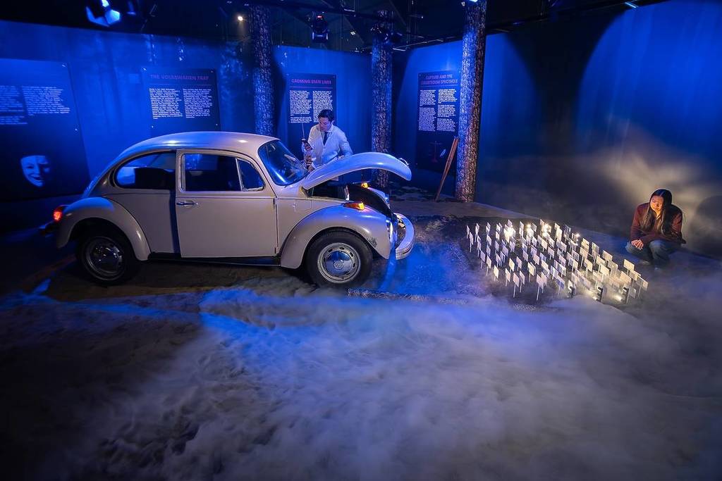 a man and woman look at a recreation of Ted Bundy's car among fog at Mind of a Serial Killer exhibition