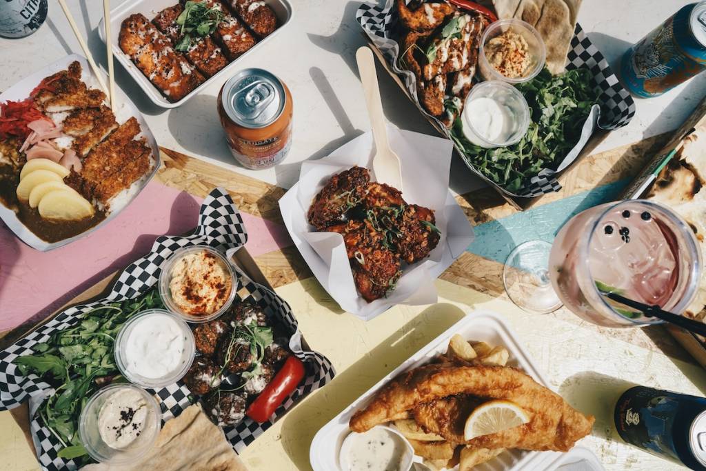 Various food in takeaway containers, with drinks spread across the table