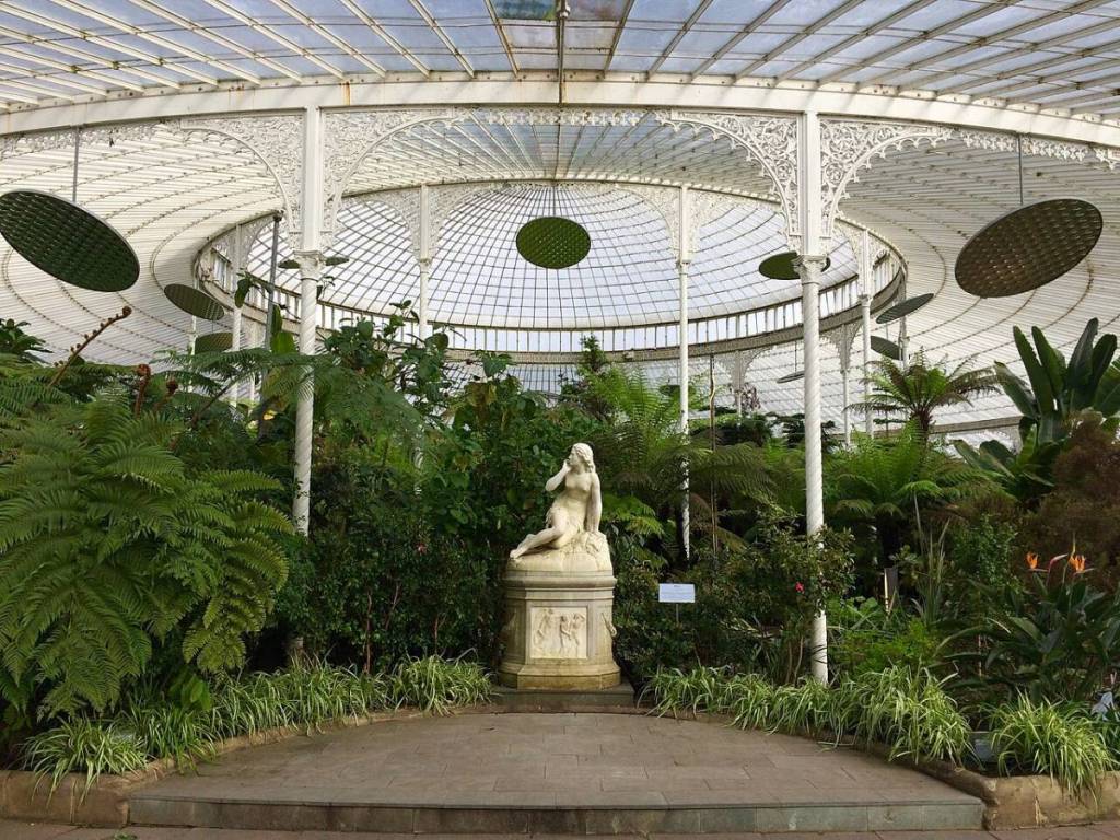 Inside a greenhouse in Botanic Gardens, with a statue of a woman posing surrounded by plants