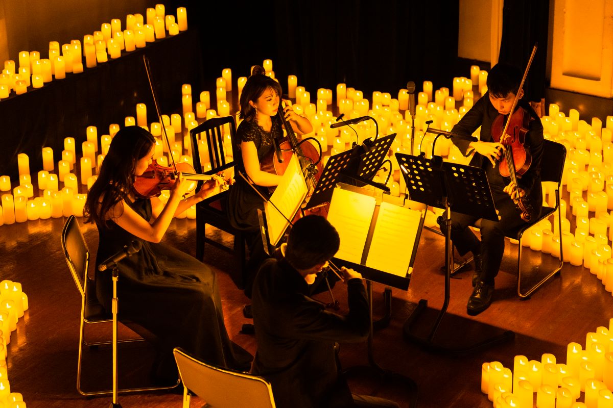 Streichquartett spielt auf der Bühne bei einem Candlelight-Konzert, umgeben von etlichen Kerzen