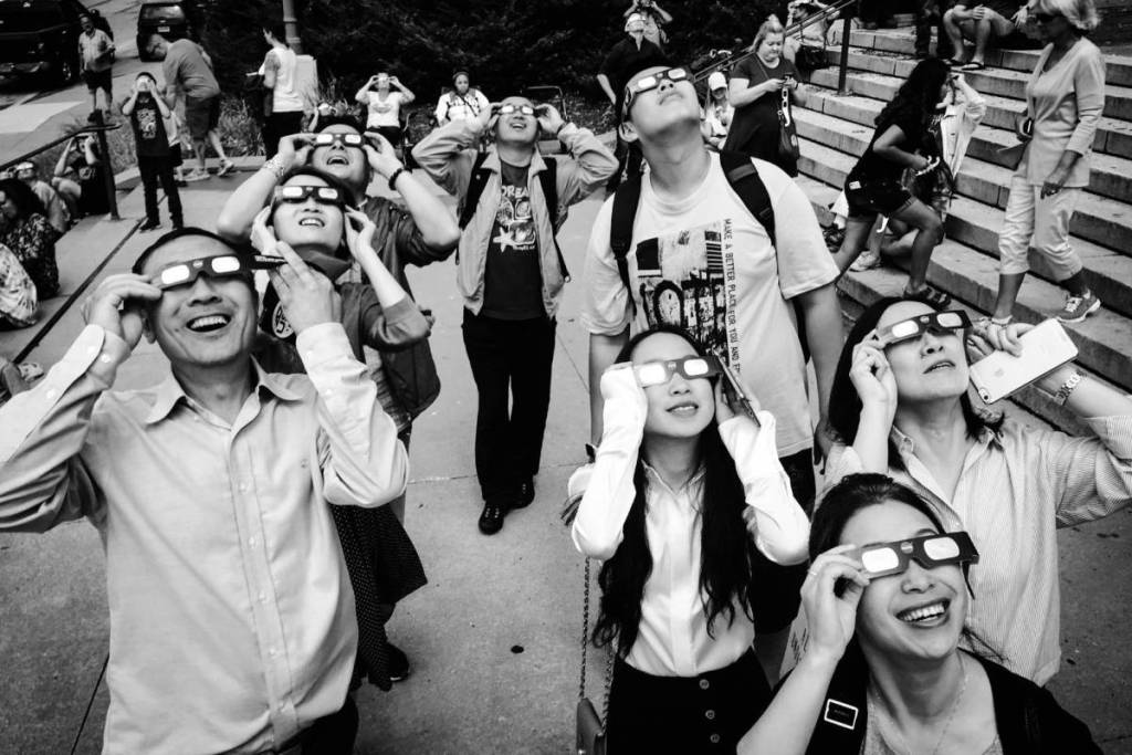 A group of people looking up at the sky through solar eclipse glasses