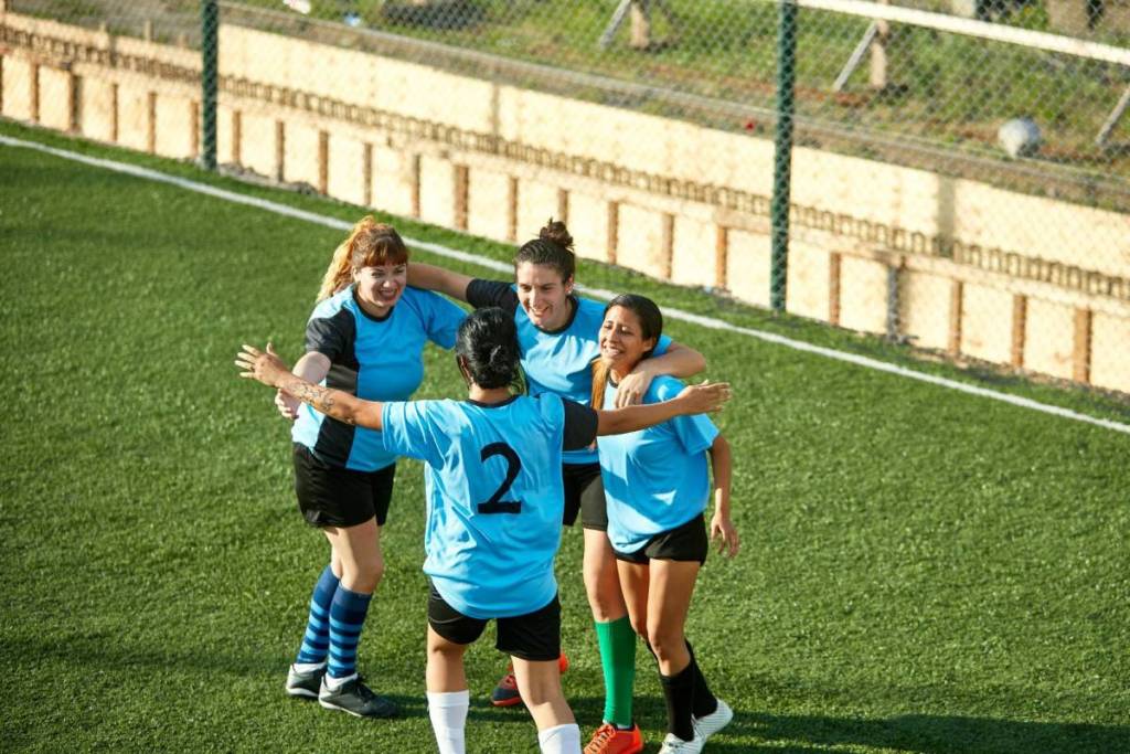 High-angle shot of cheerful female soccer players hugging each other