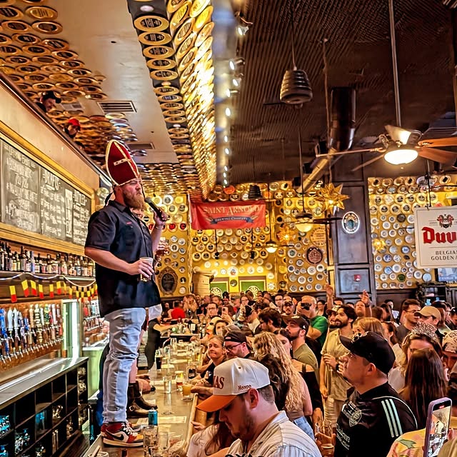 La imagen muestra a una persona hablando con un grupo de gente dentro del Flying Saucer Draught Emporium de Houston durante una ruta de bares. 