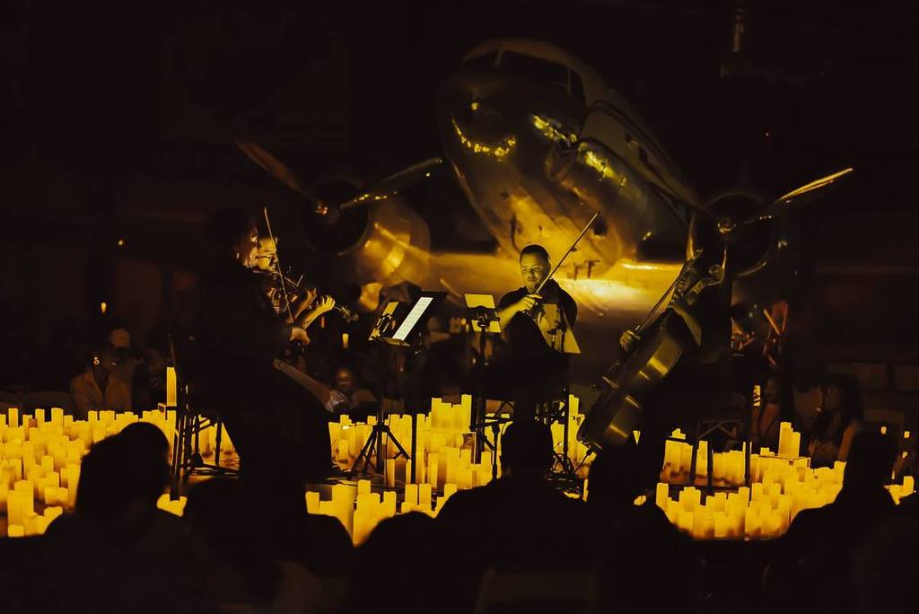 A string quartet performing a Candlelight concert under a plane at the Lone Star Flight Museum.