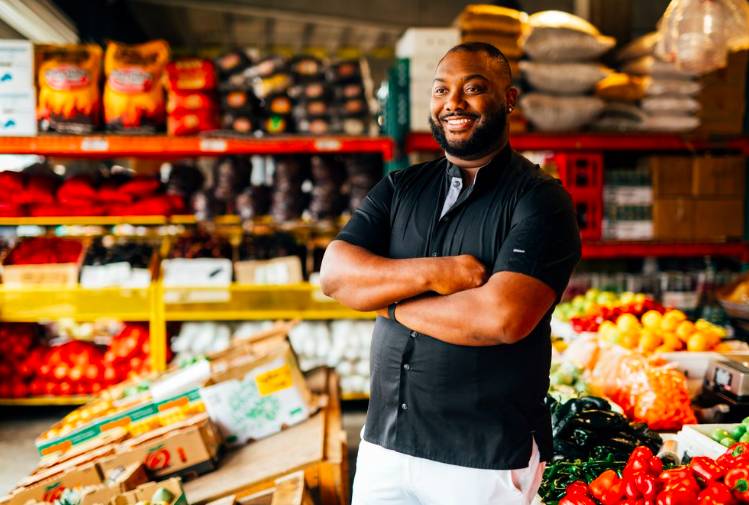 Image shows Houston-based chef and 'Top Chef' winner, Tristen Epps posing in front of produce