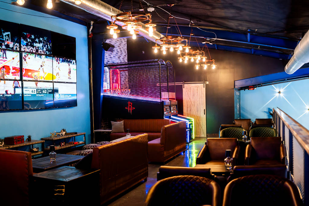 Image shows the second-story mezzanine at Drop Shots HTX with lounge seating, TVs, and sports games.