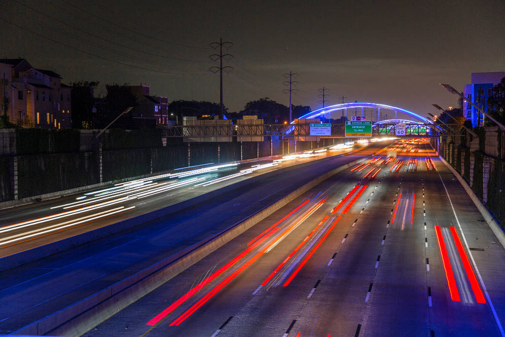 La imagen muestra una larga exposición de coches circulando por una autopista de Houston por la noche.