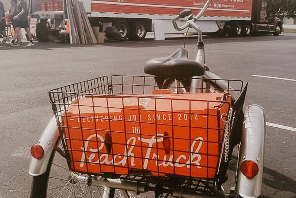 Image shows a package from the Peach Truck is the basket of a bicycle.