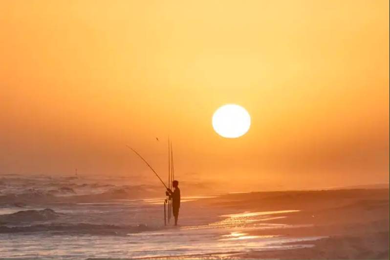 Image shows a person fishing at Matagorda Beach in Texas