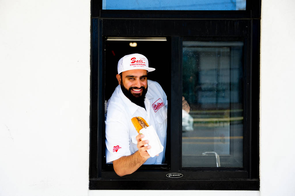 Image shows Burger Bodega and Bas's Cheesesteaks founder, Abbas Dhanani, at the pick-up window of Burger Bodega in Houston