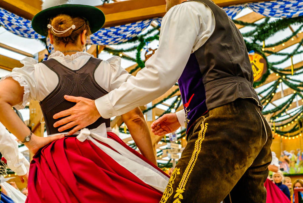 Image shows a couple in Leiderhousen at an Oktoberfest party.