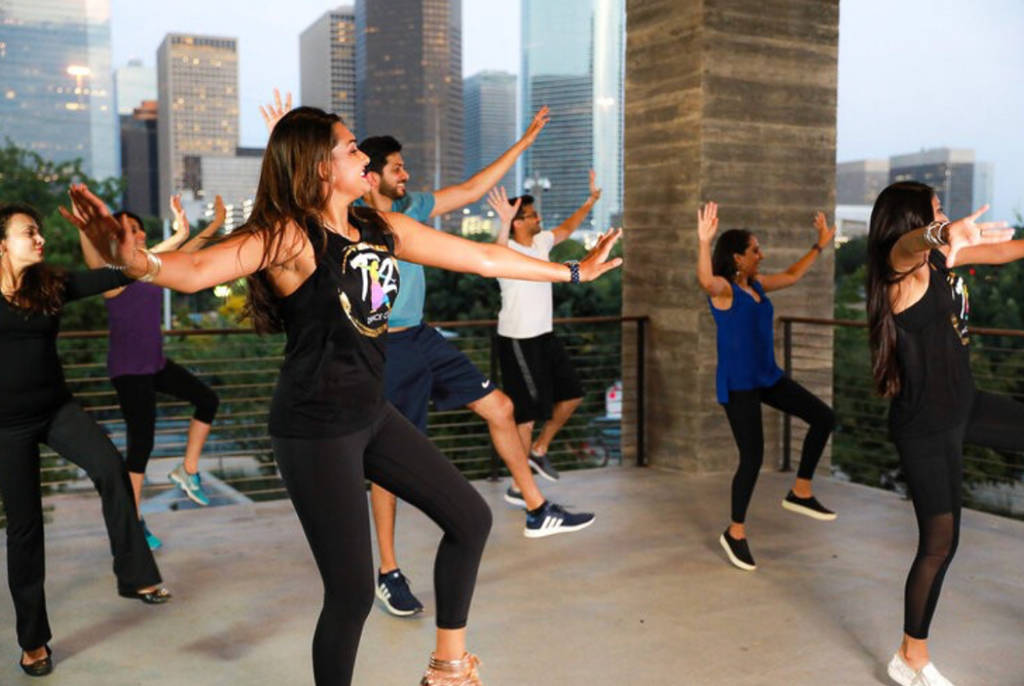 La imagen muestra a un grupo bailando en una azotea.