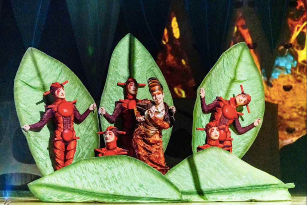 Image shows actors dressed in costumes as insects in front of leafs for the 'OVO' production by Cirque du Soleil