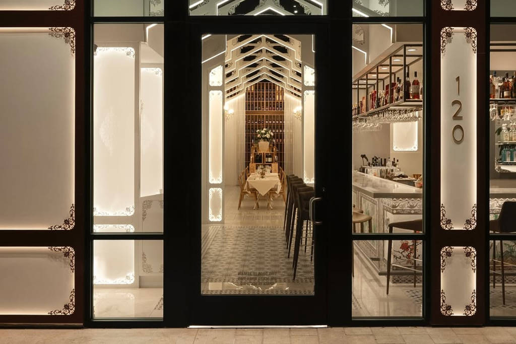 La imagen muestra el interior de Annam en Houston a través de la puerta principal de cristal.